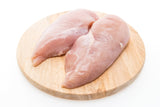 Two pieces of chicken breast plated on a wooden board